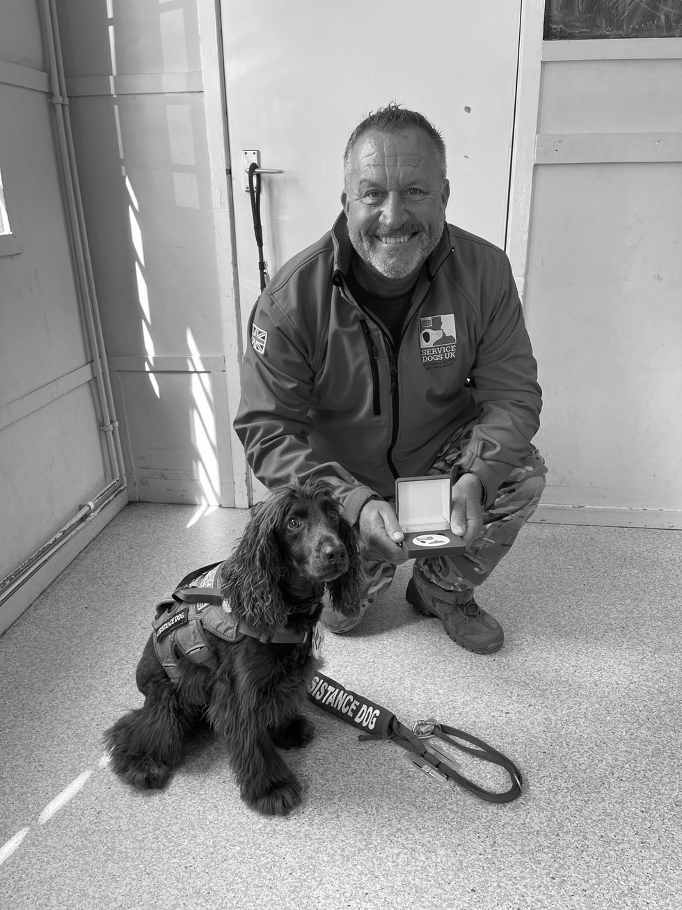 a man presenting a medal next to a service dog