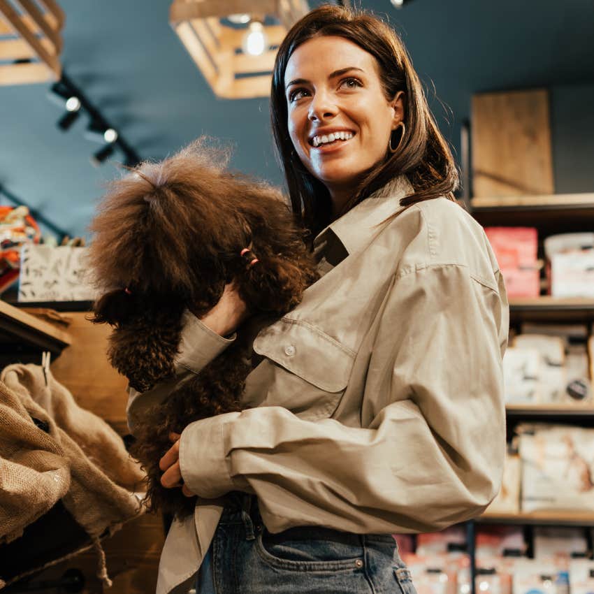 Dog owner holding her dog in a public space. 