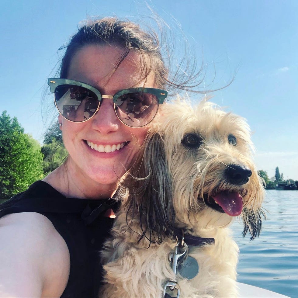 a person with sunglasses enjoying time with a dog by the water