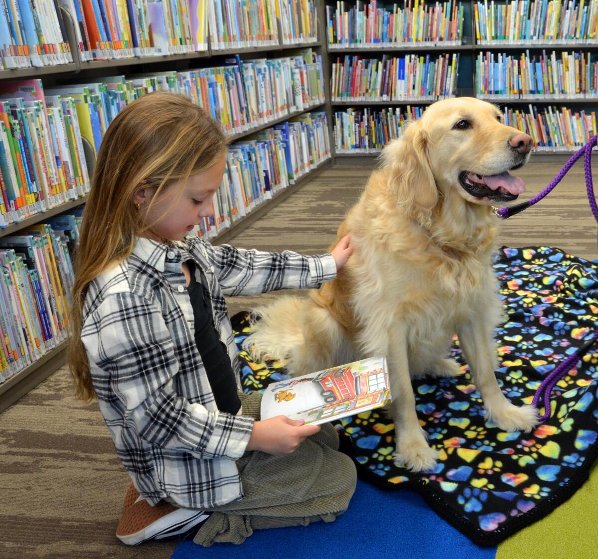 Fynlee Wentz reads to Harlow during the BARK event Tuesday at the Corona del Mar branch of the Newport Beach Library.