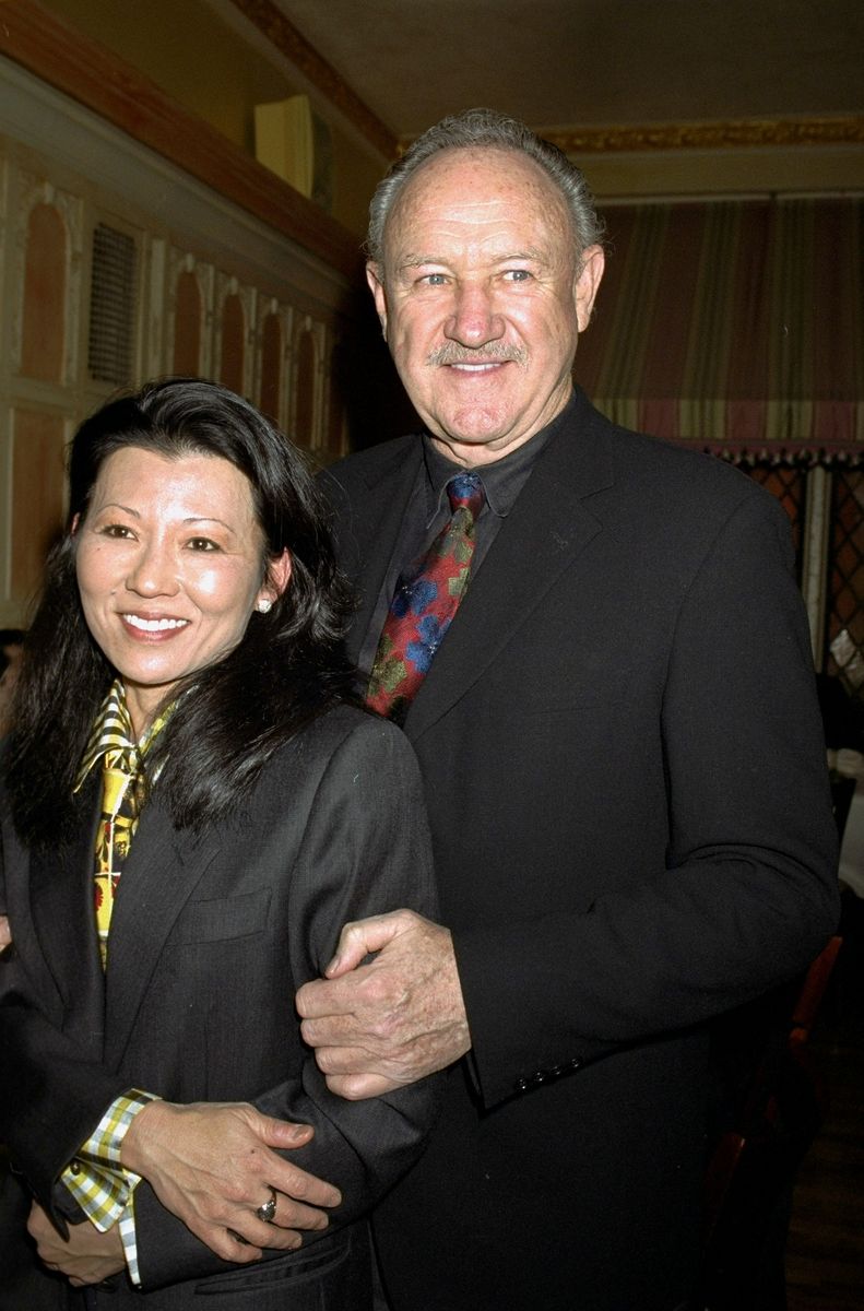 Actor Gene Hackman with wife Betsy Arakawa at the United Cerebral Palsy of New York City's 15th annual Champagne Stakes at Etoile restaurant on E. 56th St.Gene Hackman in a black suit with a colorful tie, standing with his wife Betsy Arakawa, who wears a dark suit with a patterned tie, both smiling at a formal event.