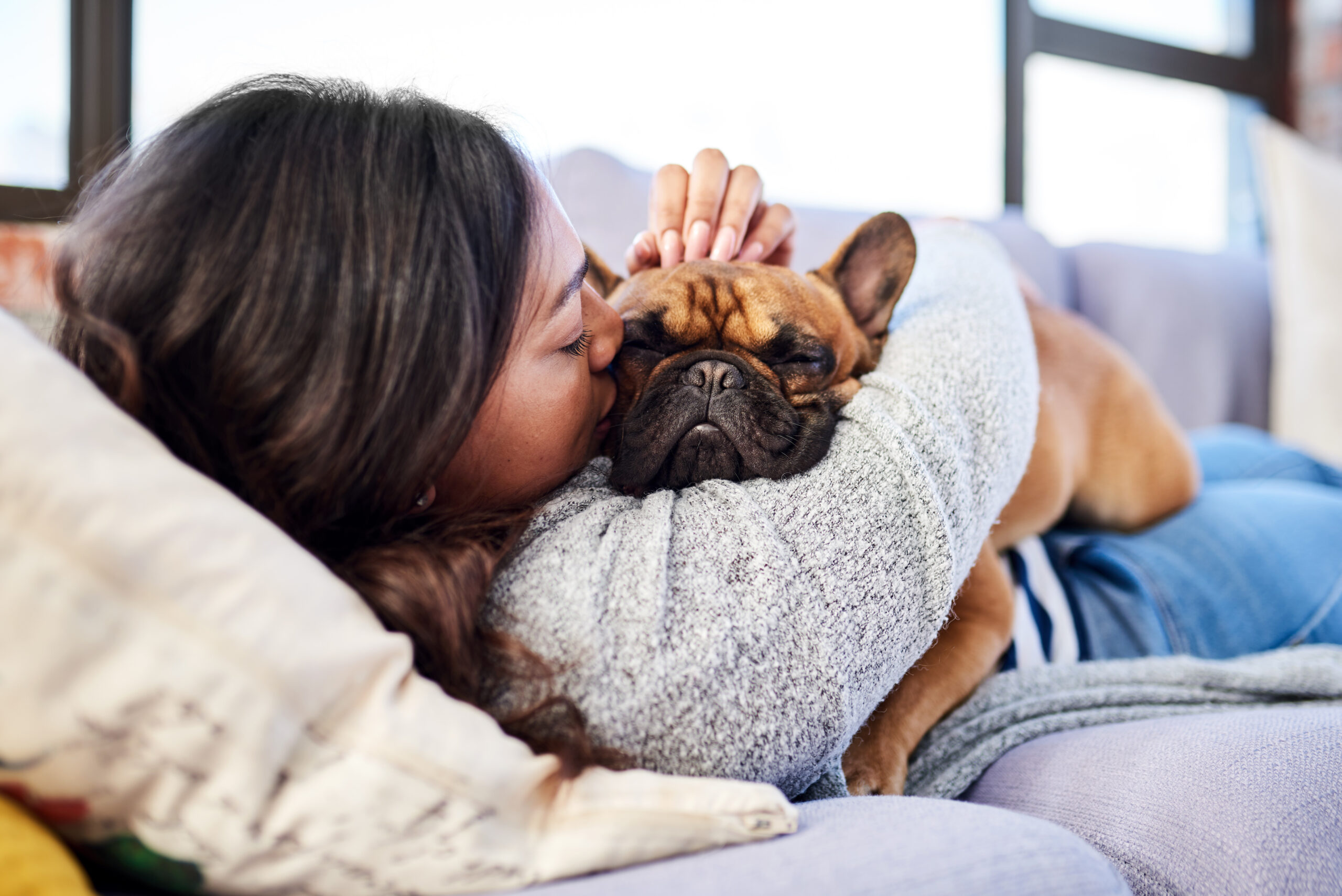 Woman cuddling her dog on a couch.