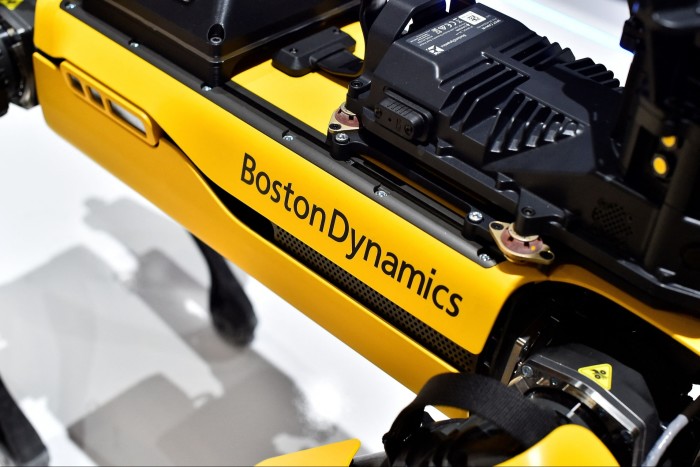 Boston Dynamics logo on the side of a yellow robotic dog with visible technical components
