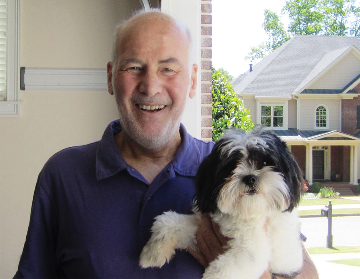Michael Quattrochi smiles, holding a fluffy dog in his left arm
