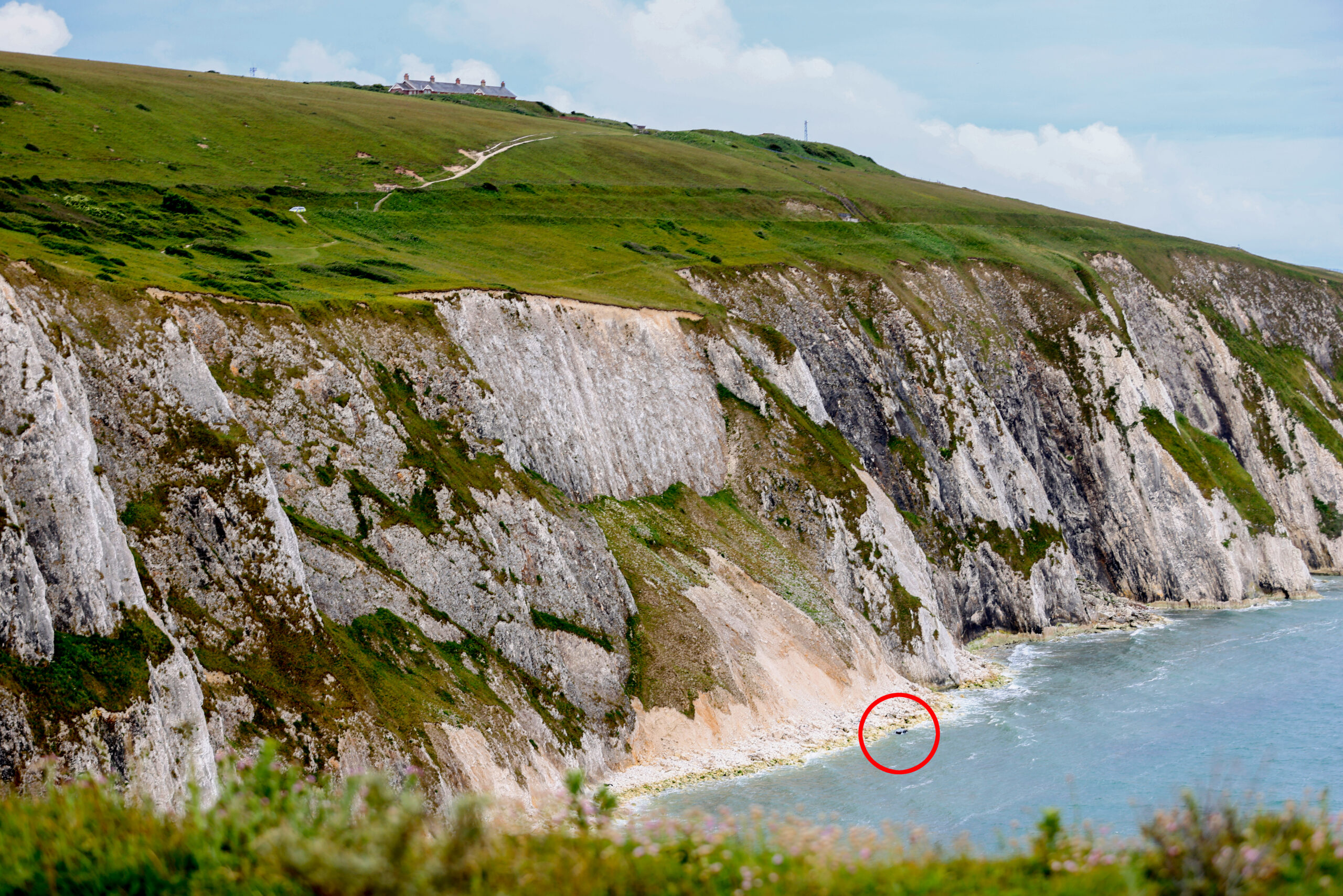 Car at the bottom of a cliff near the ocean.