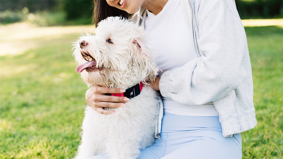 A woman with a dog wearing a Fi dog collar