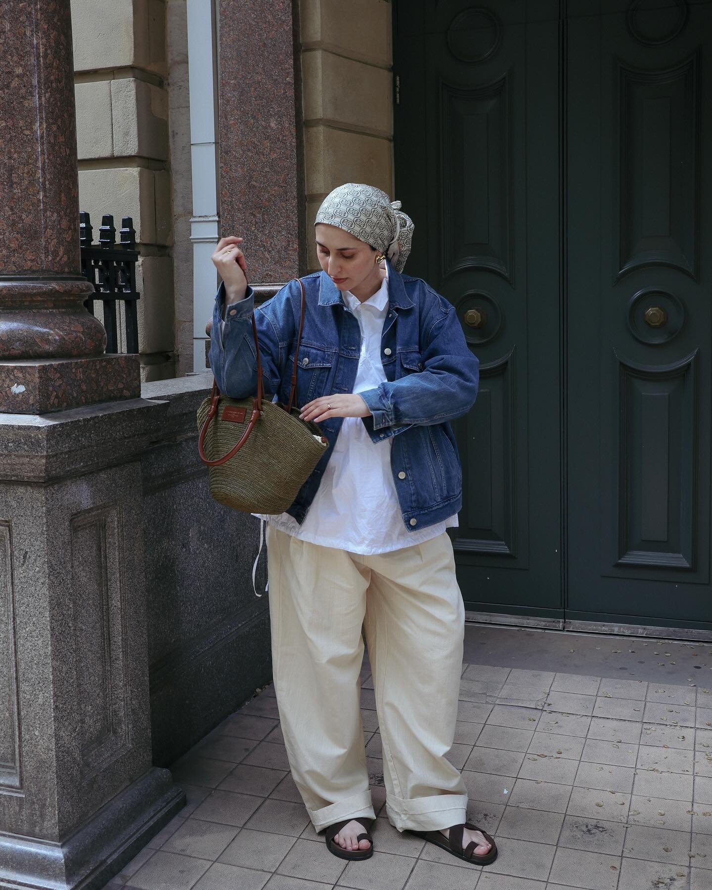 Woman wears denim jacket, yellow linen trousers, black sandals, basket bag